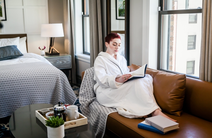 A woman reading on a couch in her suite at the Heathman Hotel in Portland, Oregon.