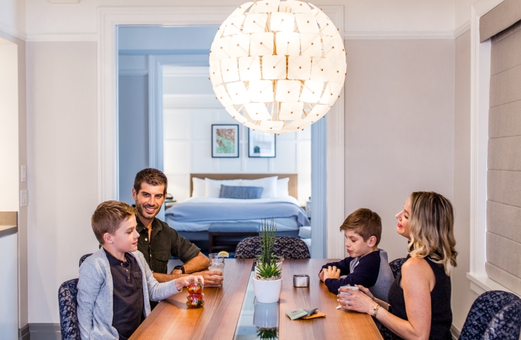 A family sitting at the dining table in a suite at the Heathman Hotel in Portland, Oregon.