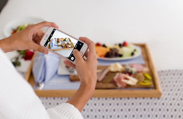 A person taking a photo of their room service breakfast.