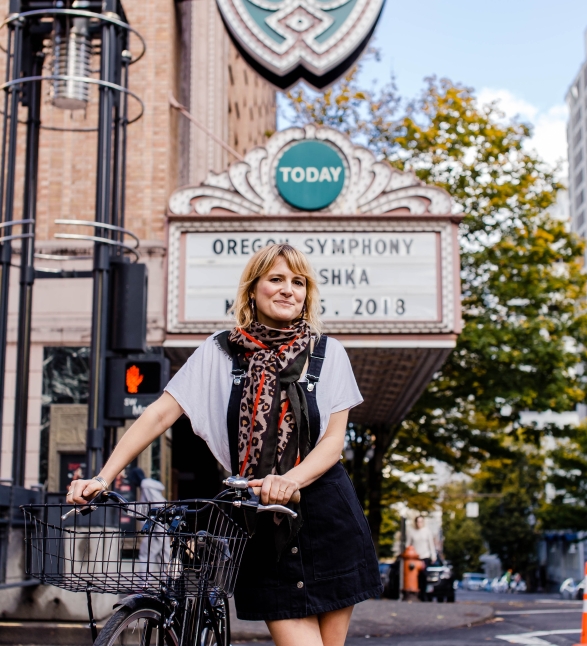 A woman standing on the street with her bike.