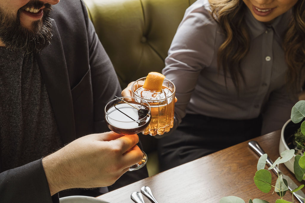 Two people toasting with cocktails.